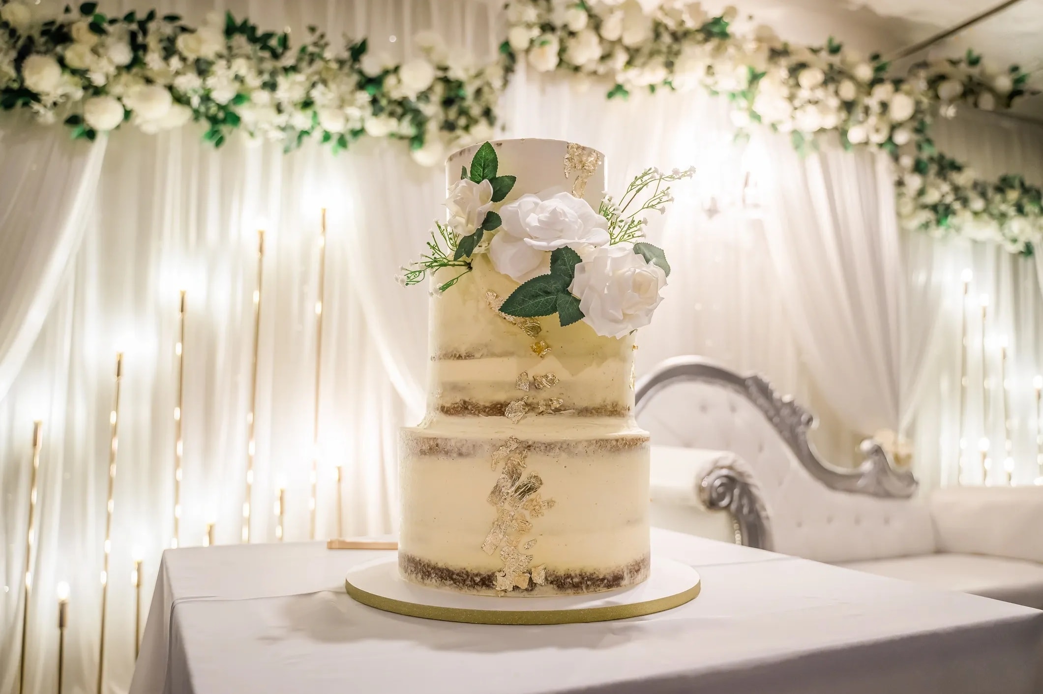 Gilded Elegance — Three-tier semi-naked cake with gold leaves and fresh blooms